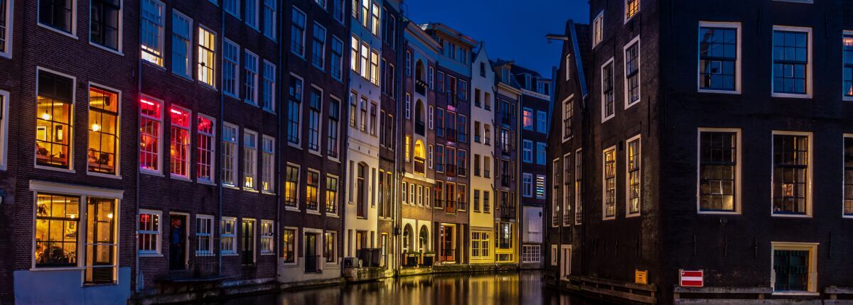 Lichter einer europäischen Stadt spiegeln sich nachts im Wasser